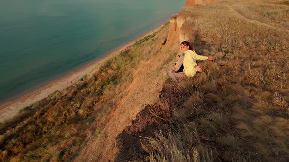 Happy Carefree Woman with Dog Sitting on Cliff and Enjoying Amazing View Above Sea Water