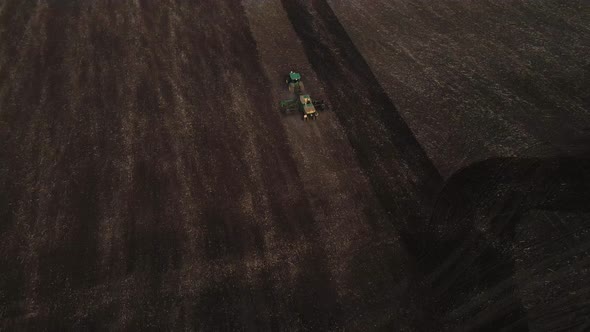 Aerial view, drone view of green tractor with plough working on a field,