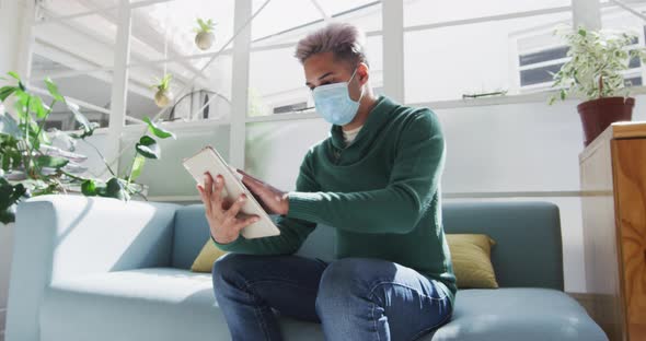 Man wearing face mask wiping his digital tablet with a tissue