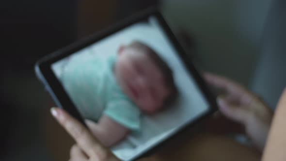 Slow Motion of Woman Looking at Her Baby on Her Tablet From Baby Monitor