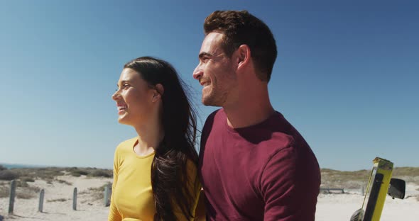 Happy caucasian couple sitting in beach buggy by the sea talking