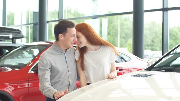 Happy Couple Chooses First Family Car To Buy in a Showroom