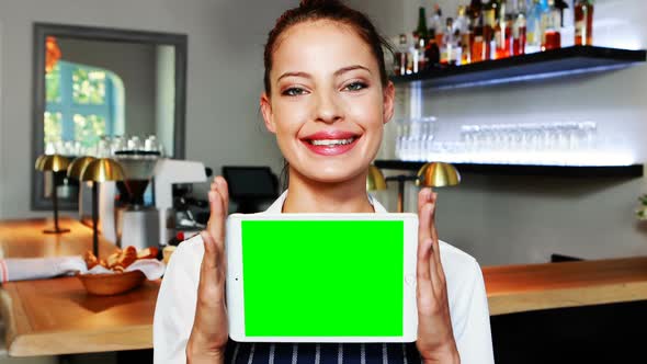 Portrait of beautiful waitress holding digital tablet at counter