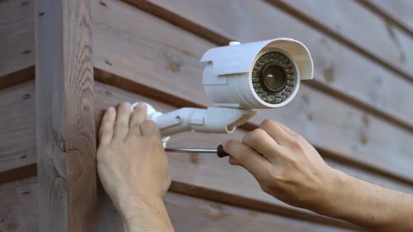 Technician installing wireless CCTV camera security system at house.