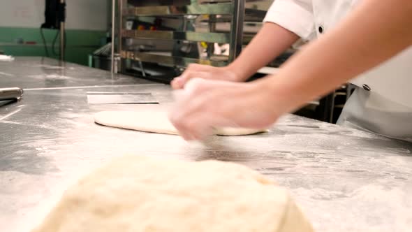 Chef is preparing pastry dough, baking bakery food on a stainless steel table.