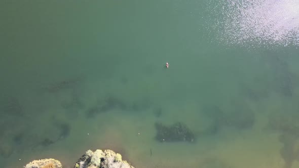 A lonely kayaker paddling on a large lake, seen from above