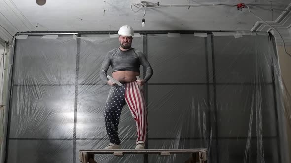 Fat Bearded Adult Man in Protective Helmet and USA Flag Print on Pants Remove Construction Whitewash