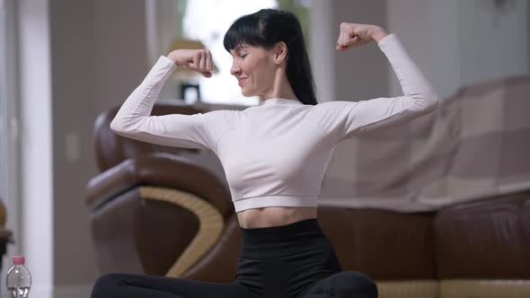 Happy Satisfied Sportswoman Showing Strength Gesture Smiling Looking at Camera