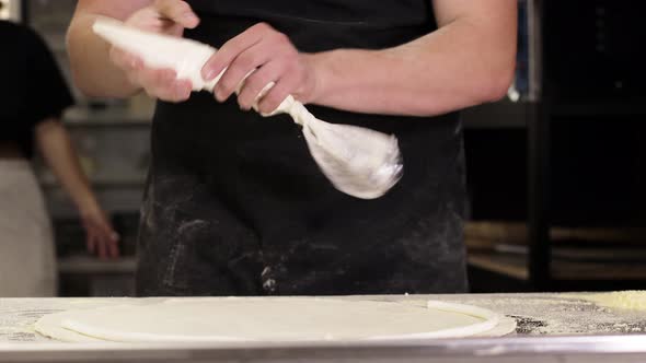 The chef's hands wrap the cheese rim in the raw pizza dough. Making pizza with cheese side.