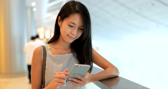 Woman looking at cellphone and walking in the shopping mall