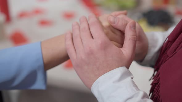 Closeup of Unrecognizable Man and Woman Holding Hands at Valentine's Dinner Table