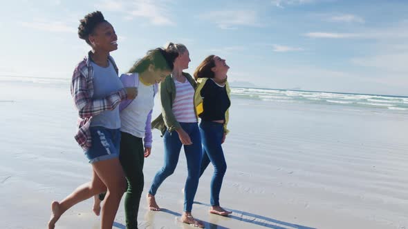 Happy group of diverse female friends having fun, walking along beach