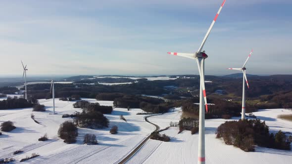 Aerial shot of rotating wind turbines during sunset.