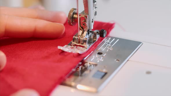Hands of Woman Tailor Sewing Red Clothing on Sewing Machine with Straight Seam