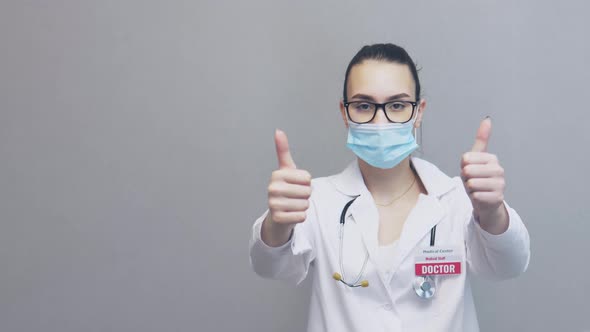 Young Female Doctor in Uniform Glasses Facial Mask Showing Two Thumbs Up Sign