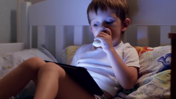 Closeup Video of Little Toddler Boy Watching Cartoons on Digital Tablet Computer and Eating Banana