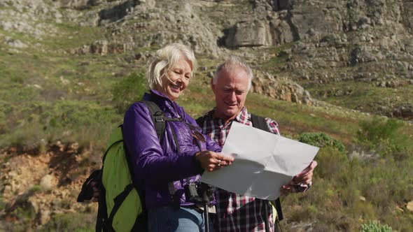 Active senior couple looking map on mountains