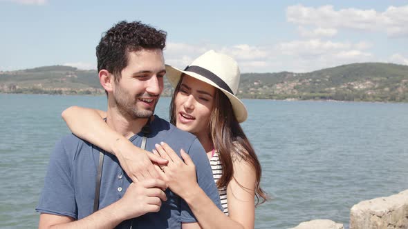 Smiling woman embracing boyfriend at lake in summer