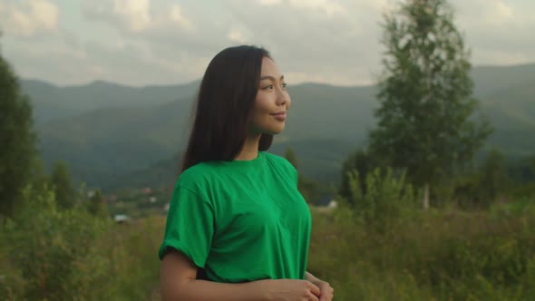 Lovely Positive Asian Female Smiling Over Scenic Mountain View at Sunset