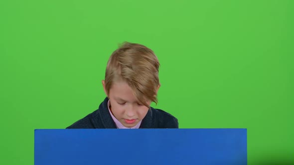 Teenager Gets Up From Behind the Board Looks at It and Shows Dislike on a Green Screen