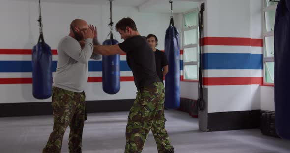 Caucasian man learning self defense from trainer in gym