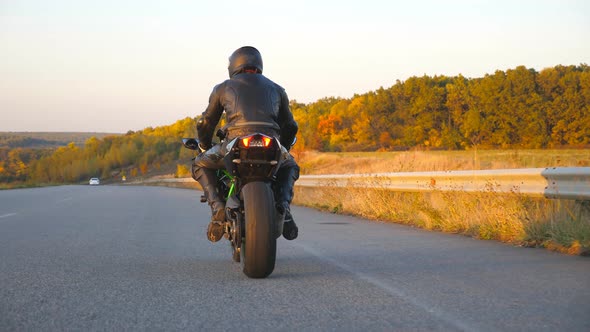 Unrecognizable Man Riding on Modern Sport Motorbike at Autumn Highway. Motorcyclist Racing His