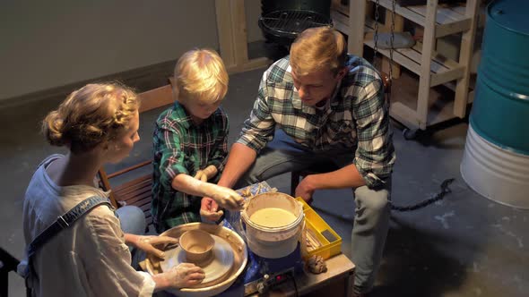 Slow Motion, Woman Teaches Man and Boy To Work with Pottery Wheel