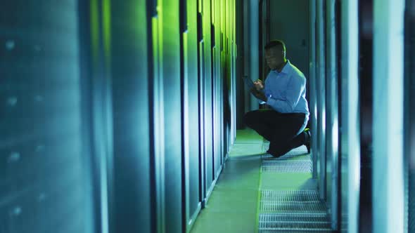 African american male computer technician using tablet working in business server room