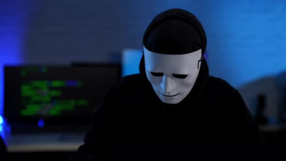 Unrecognizable Hacker in Anonymous Face Mask Raising Hands Up