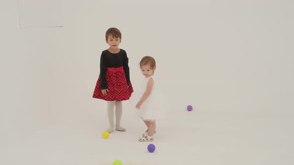 Toddler Girl Wearing Diaper and Her Sister Playing with Balls