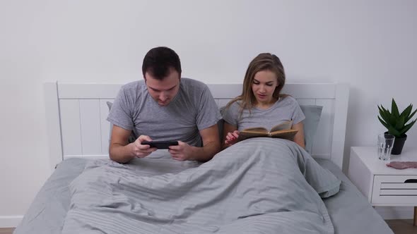 Portrait of Happy Young Couple Posing While Lying in Bedroom on Bed