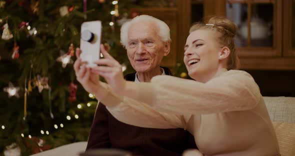 Cheerful Woman Taking Selfie With Grandfather During Christmas