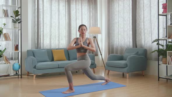 Young Asian Athletic Female Exercising, Stretching And Practicing Yoga On The Mat At Home