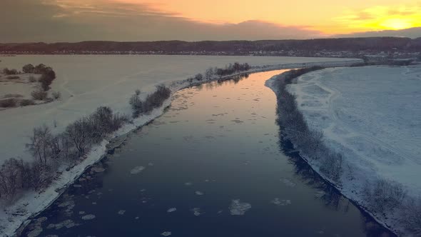 Amazing winter landscape with red sunrise. Drone flying over the river