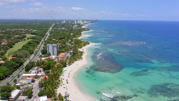 Aerial forward view of white sandy beach and turquoise sea of Juan Dolio in Dominican Republic. Aeri