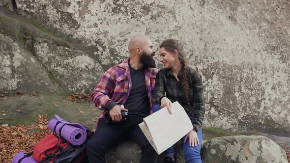 Traveler with a Camera, Tourist Map and Backpack, Have Fun Sitting on the Top of the Mountain