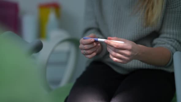 Pregnancy Test in Hands of Teenage Girl Sitting on Gynecological Chair Consulting Unrecognizable