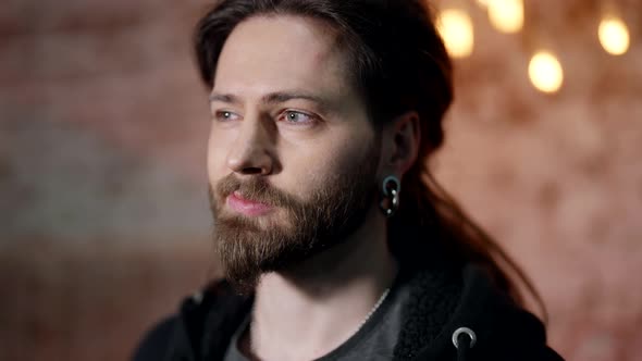 Portrait of a Surprised Man Bearded with Long Hair and Large Earrings in His Ears