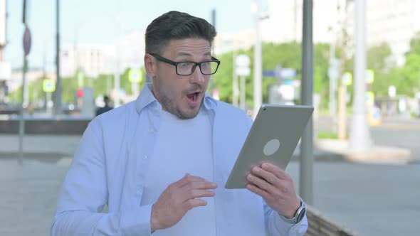 Man Celebrating Online Win on Tablet Outdoor