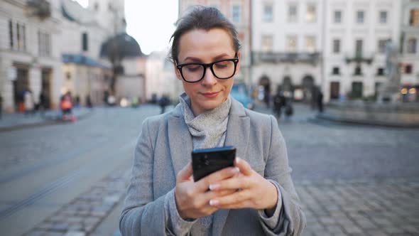 Woman Walking Down an Old Street Looking Around and Taking a Photo