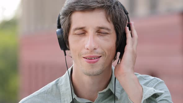 Happy Millennial Man in Earphones Enjoy Music Smiling Caucasian Young Male in Modern Headphones