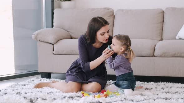 Beautiful Mother and Toddler Daughter Are Playing Construction Toys Together in a Room