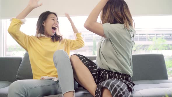 Asian couple watching TV laugh in living room at home, sweet couple enjoy funny moment.