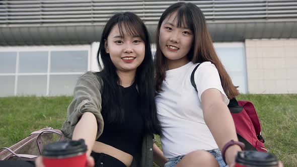 Happy Smiling Asian Girls with Coffee Cups Looking at Camera Near Urban Building