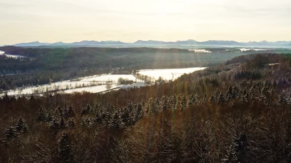 Glow on the snow at a bright sunny winter day, flying with the drone over a forest with the view at