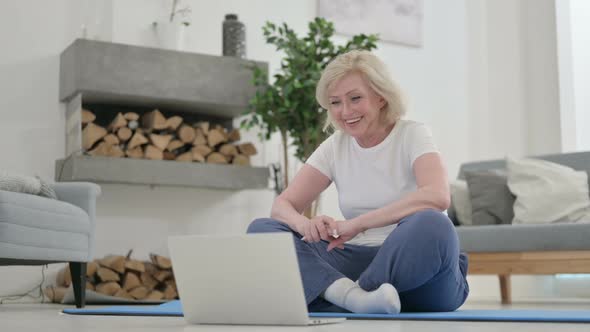 Senior Old Woman Talking on Video Call on Laptop While on Yoga Mat