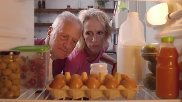 Displeased Mature Couple Searching for Food in Fridge