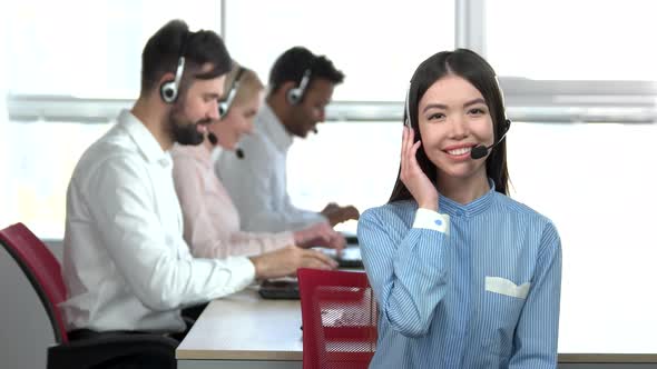 Cheerful Asian Girl in Call Center with Headset Agreeing.