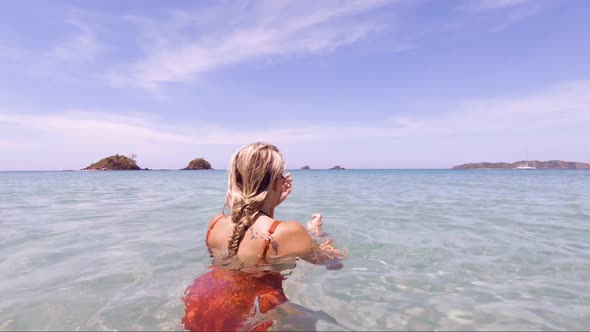 Young Beautiful Woman sits in the crystal clear oceans of Nacpan Beach in El Nido Philippines as the