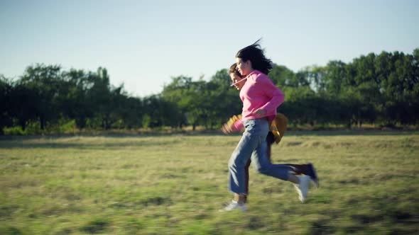 Tracking Shot Side View of Carefree Happy Teenage Boyfriend and Girlfriend Running in Sunshine on